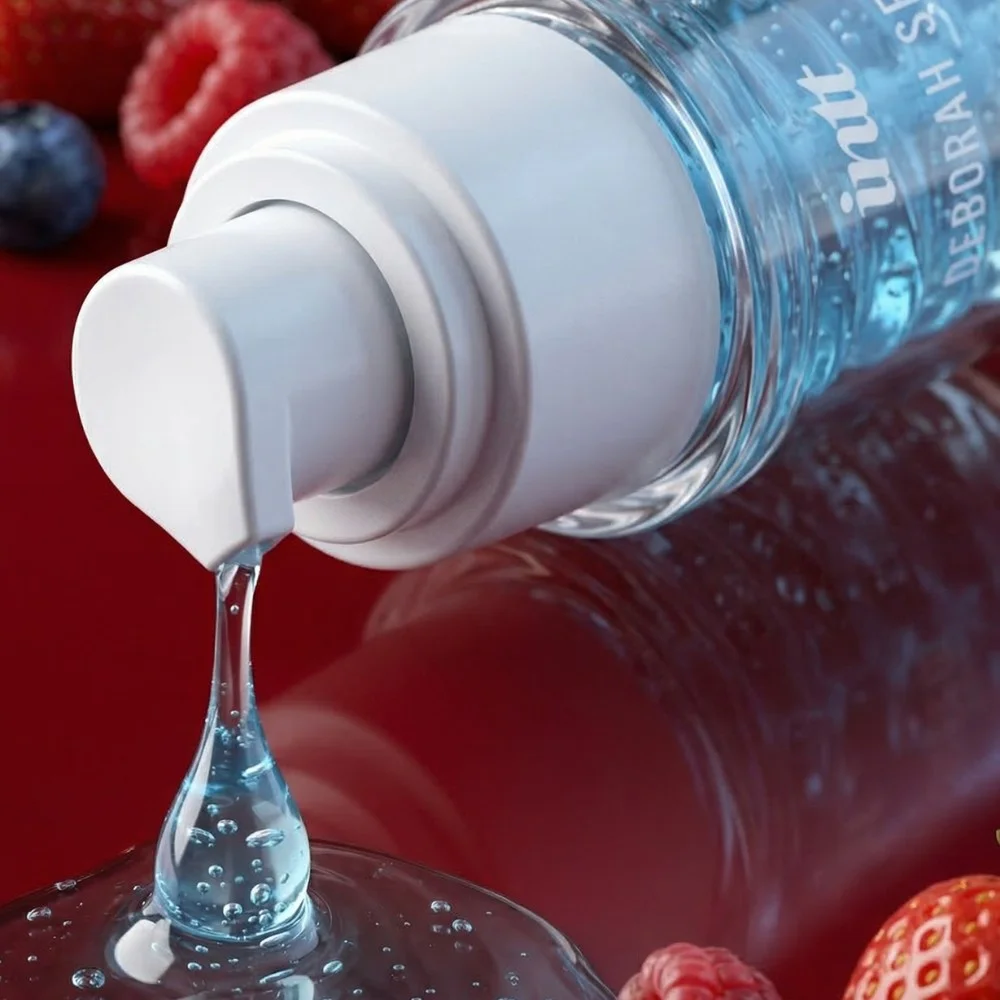 Intt O Segredo detalhe do gel azul teal sendo aplicado na mão com frutas vermelhas ao fundo